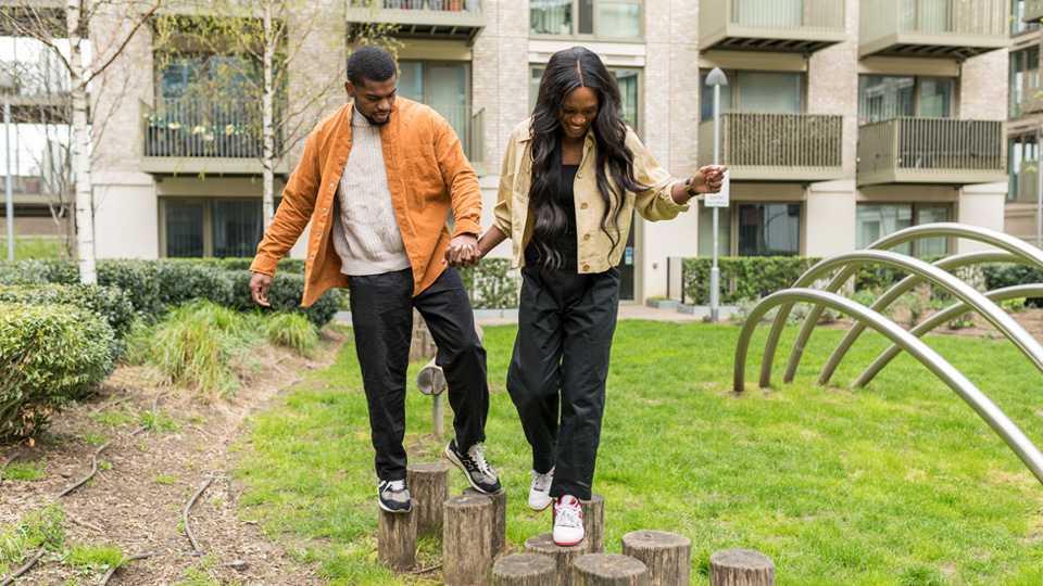 A man and woman walking over small wooden stumps
