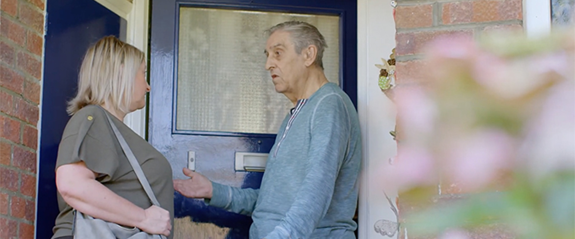 A man talking to a woman at his front door