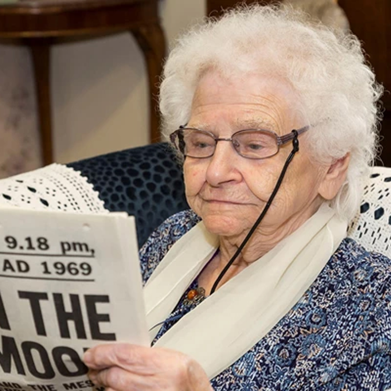 An elderly woman reading a newspaper