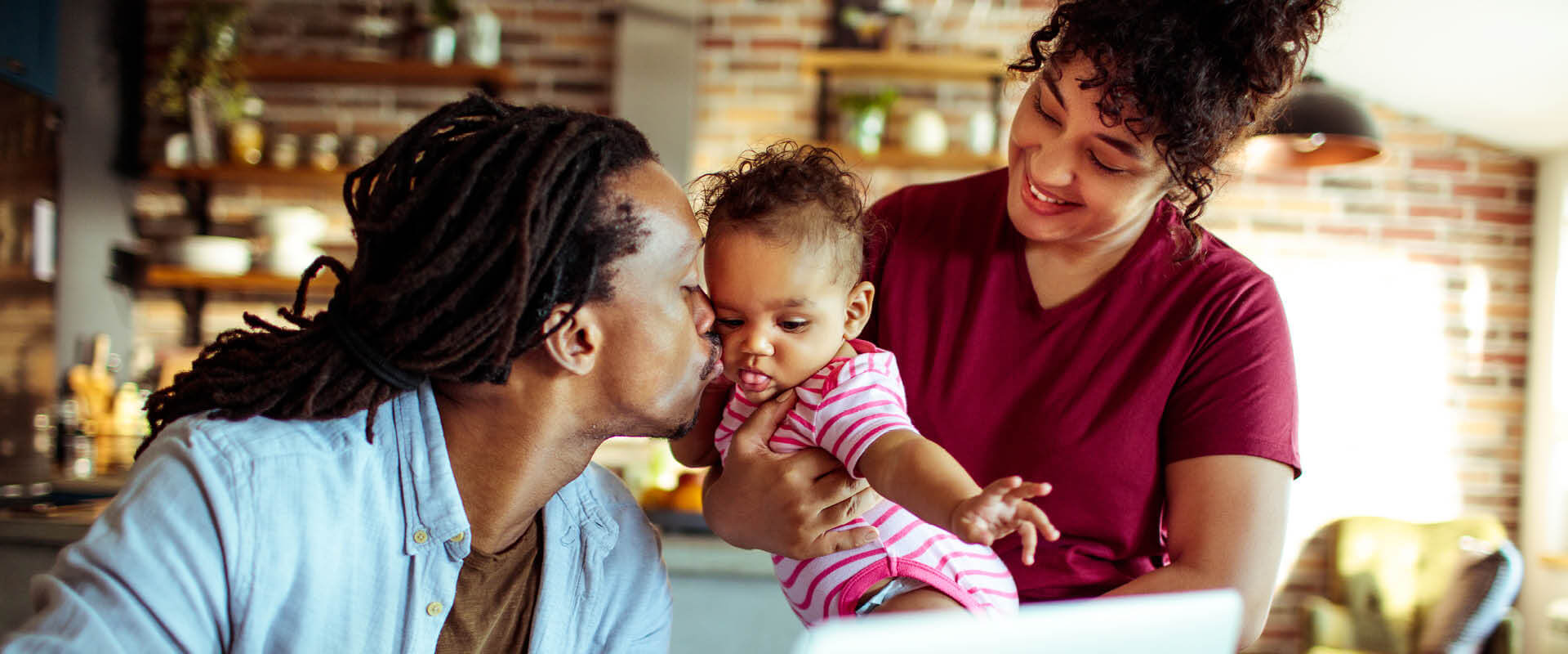 Diverse couple at home. Dad kisses daughter