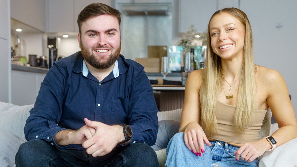 A man and woman sitting together and smiling in a living room.