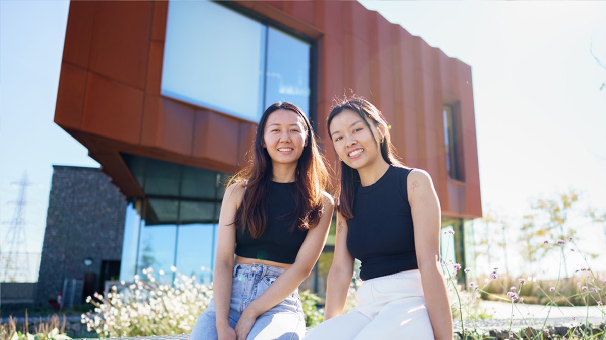 Two women smiling outside a modern residential building.
