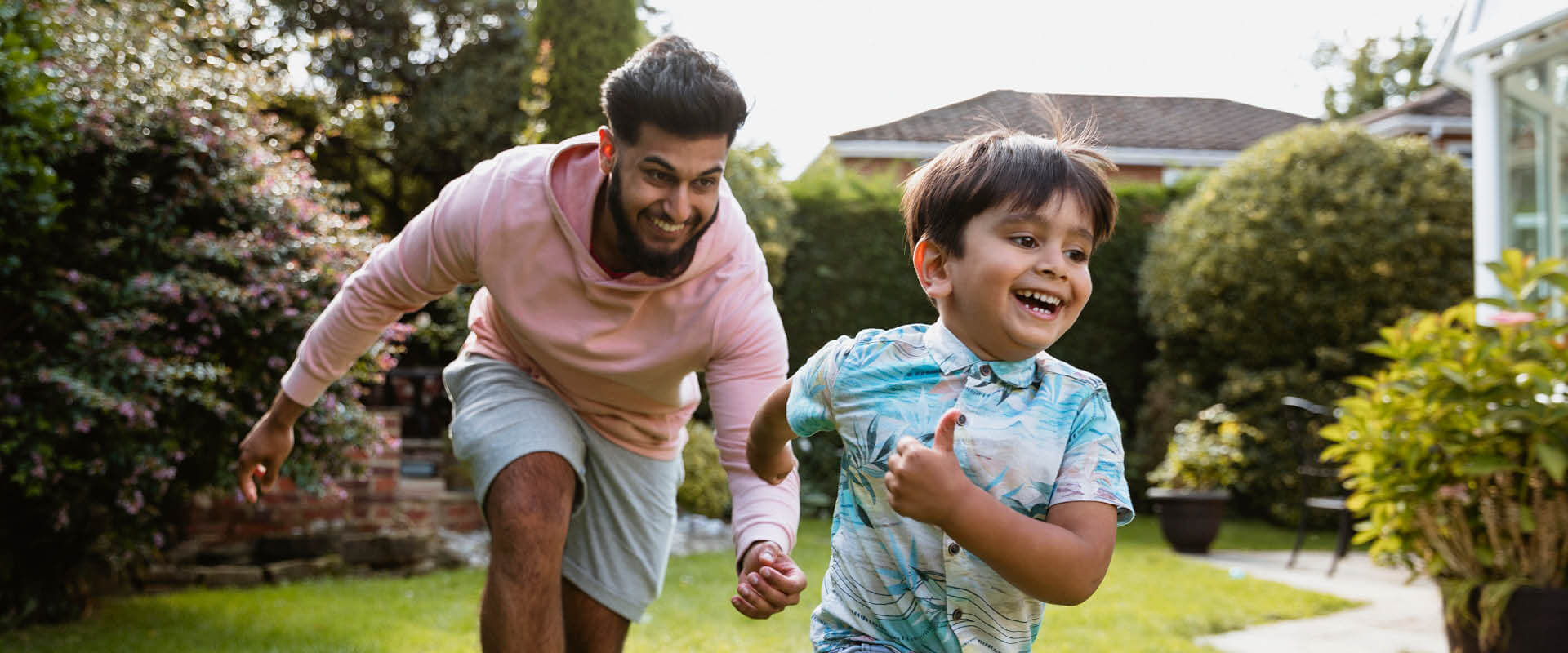 Father running after child in garden 