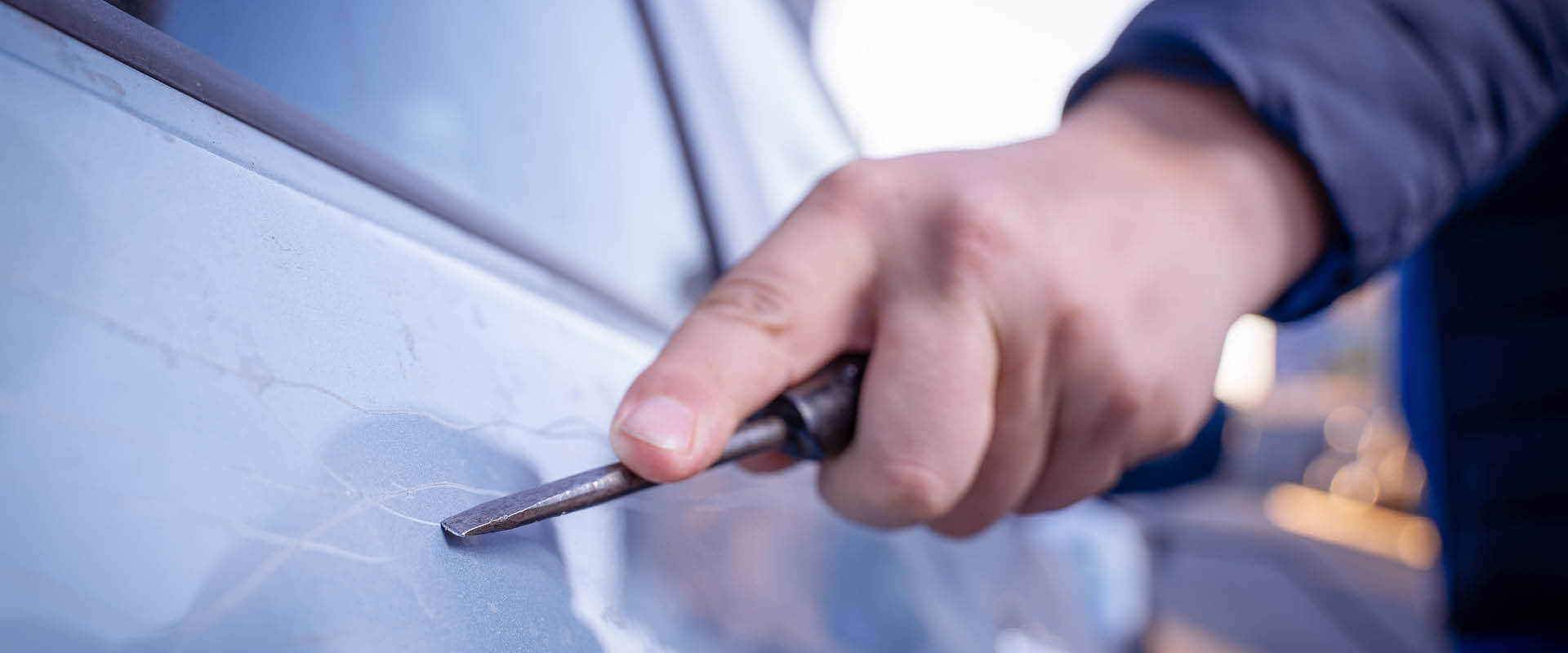 Person scratching a car with keys