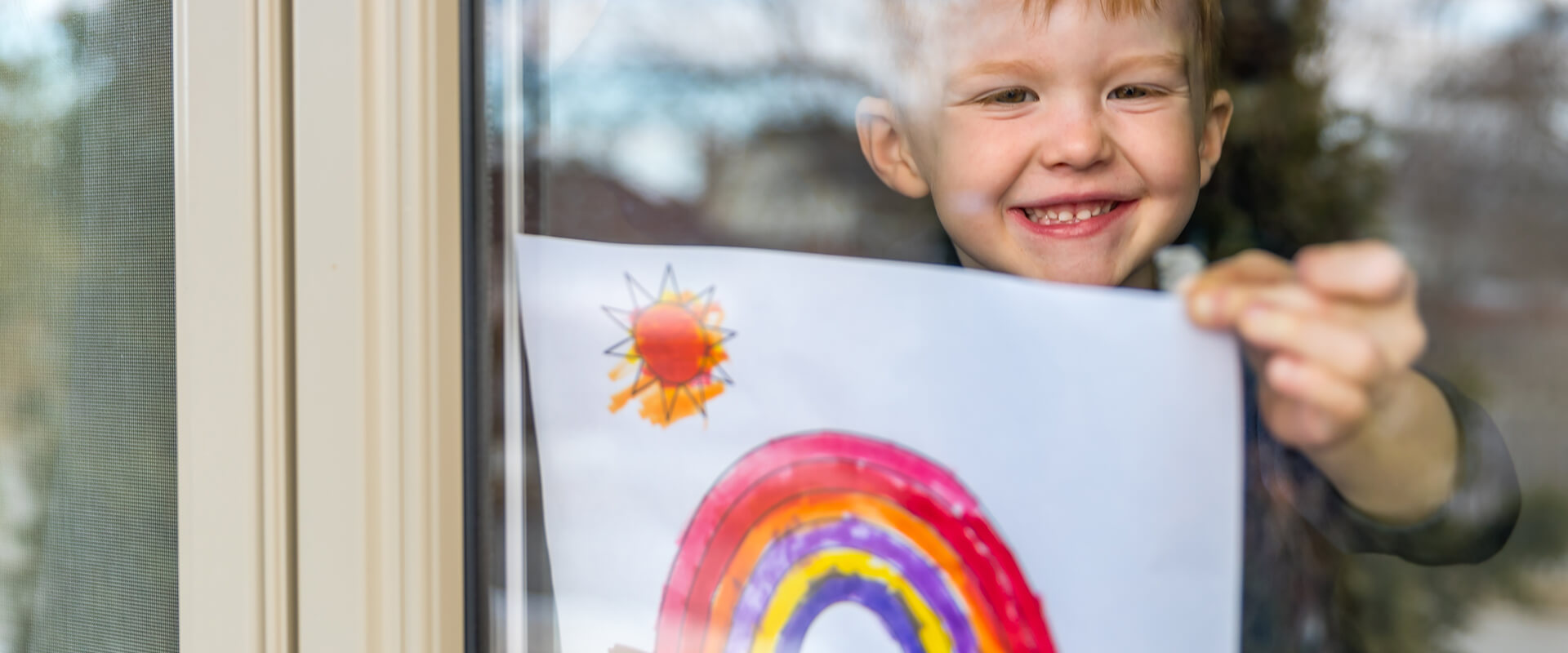 Boy holding a rainbow drawing