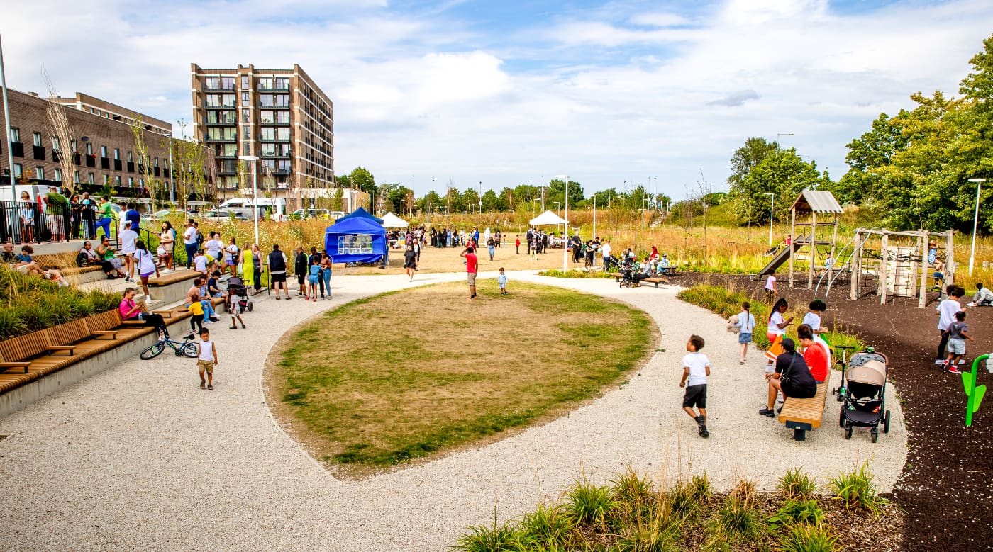 Crowd of people in a park enjoying a summer day in front of a building 