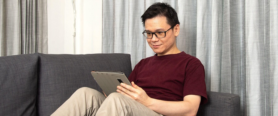 Person sitting on a sofa using a tablet device.