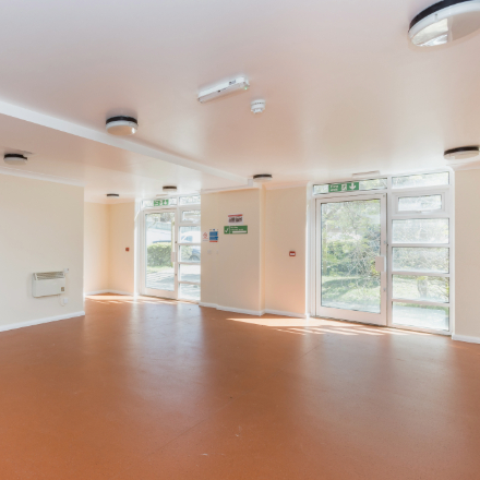 Bright communal room with large windows, multiple exits, and an open area suitable for activities and events.
