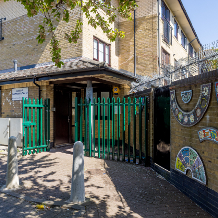 Exterior view of Loxford Community Centre, showing the entrance, green fencing, and decorative mosaic artwork on the boundary wall.