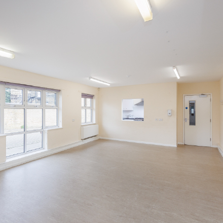 Bright, open community room with large windows, mirrored wall, and flexible space suitable for meetings, classes, workshops, and group activities.
