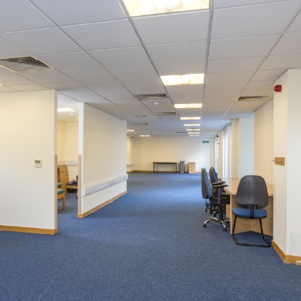 Open-plan office space with workstations, seating, and carpeted flooring suitable for meetings, training, or community activities.