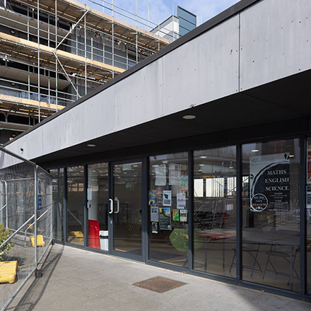 Exterior view of a modern community facility with large glass windows and construction work visible nearby.