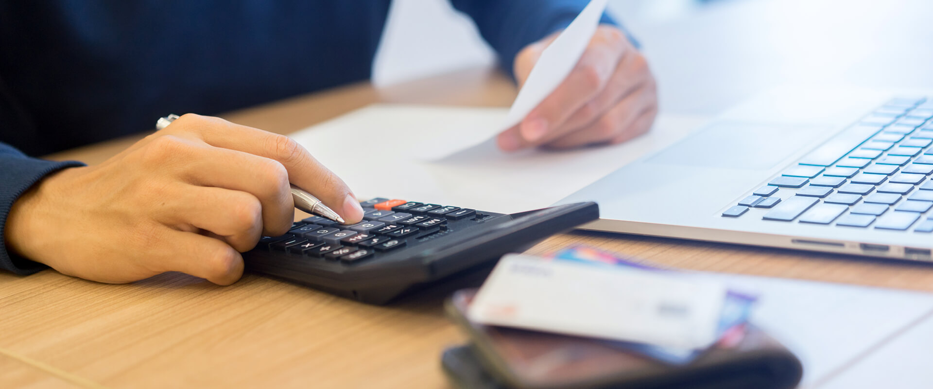 A person's hand using a calculator on a table