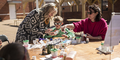 Adults and children sat around table decorating eggs for Easter