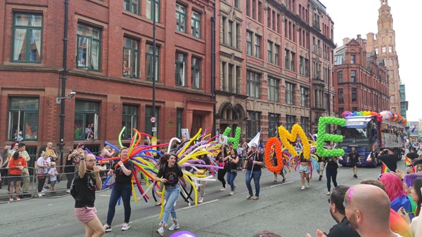 Float and crowd of HouseProud members, including L&Q staff, walking through Manchester Pride in 2022