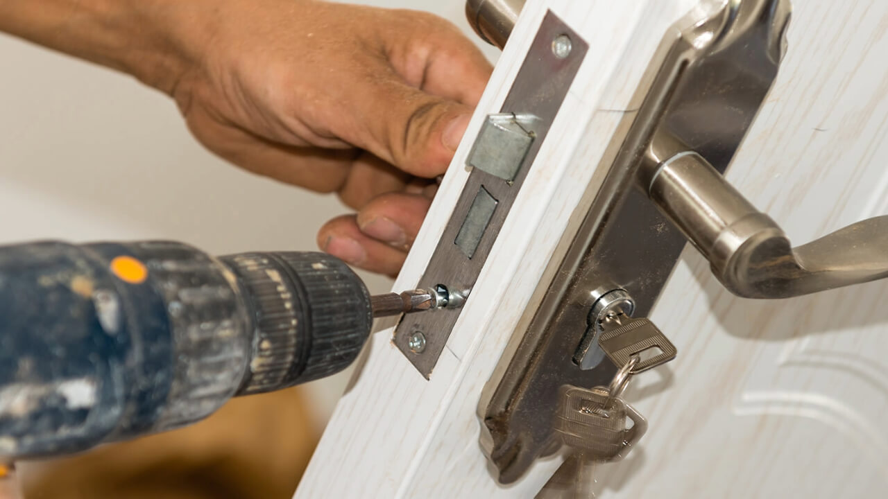 Close-up of door lock being installed with power drill