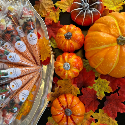 A bowl of sweets next to a variety of pumpkins