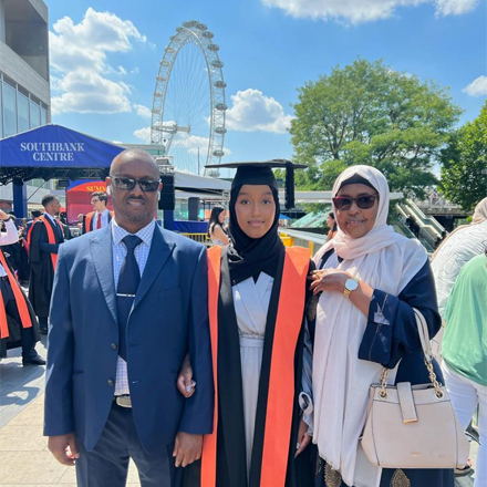 Amina, in her graduation gown, stood with her parents