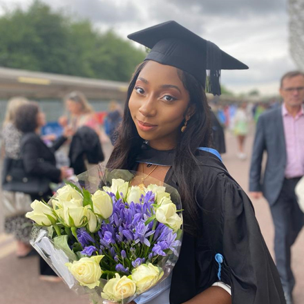 Oyindamola, holding flowers, in her graduation gown