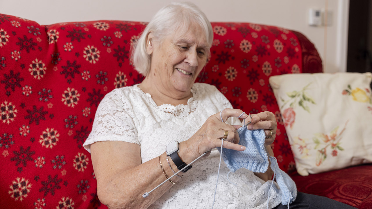 L&Q Living’s Alert and Response customer, Vera Clarke, knitting on a sofa