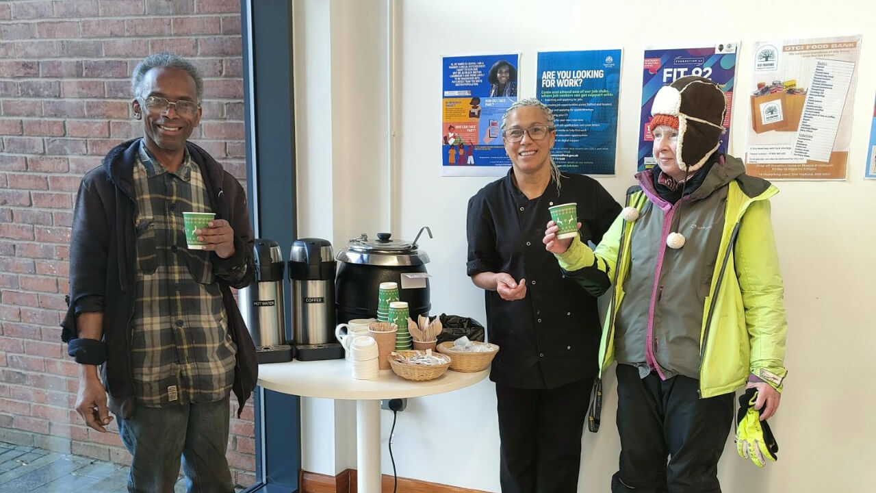 Three people holding hot drinks at a warm hub
