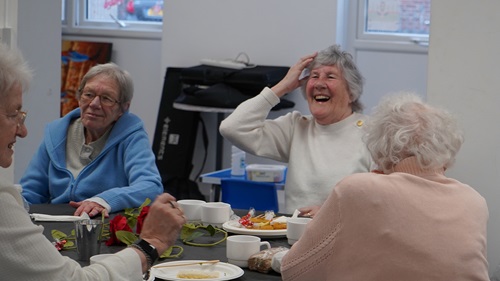 3 residents sat around a table laughing