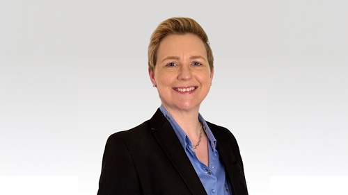 Headshot of Alyson Heald. Wearing a black blazer and blue shirt. She has short blonde hair.