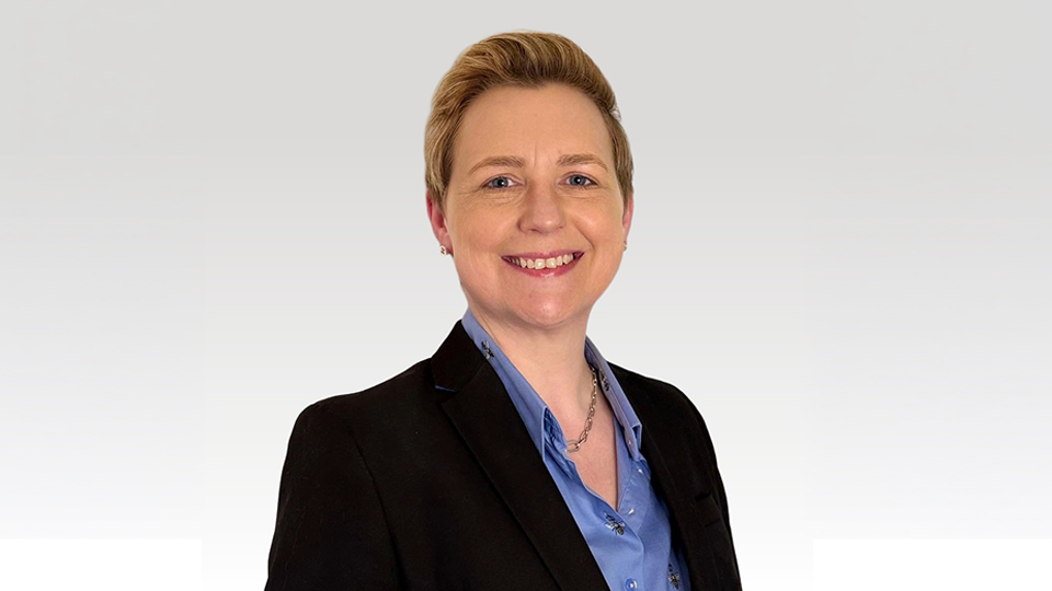 Headshot of Alyson Heald. Wearing a black blazer and blue shirt. She has short blonde hair.
