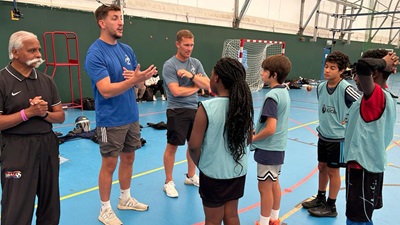 Youth group stood with leaders at indoor basketball event
