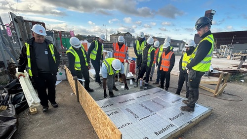  Workshop attendees inspect insulation materials under expert guidance at Bauder’s roofing event.