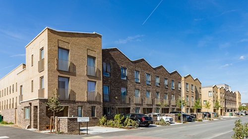 Three‑storey brick residential buildings with parked cars along a sunny street in Beam Park