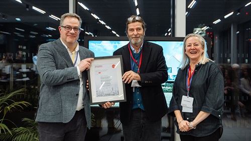 Close-up of three individuals holding and presenting an award certificate, celebrating the recognition of their project.