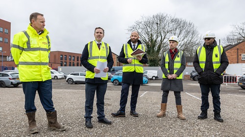 Group of site staff in high‑visibility clothing standing on a construction area.