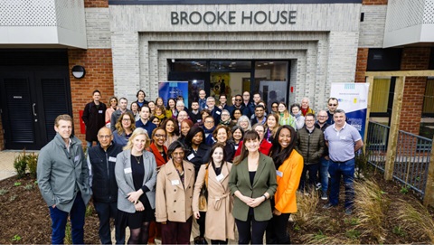 Large group of people gathered outside Brooke House posing for a group photo at the building entrance.