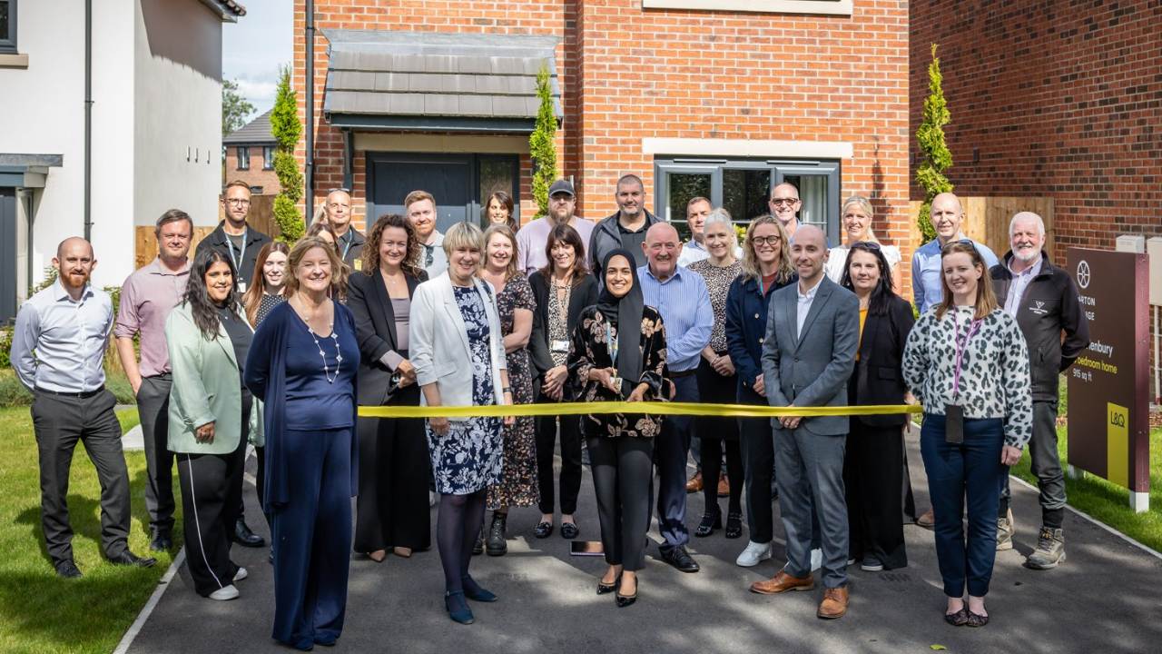 Large group of people standing behind a yellow ribbon