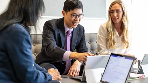 Three people looking at laptops on a coffee table