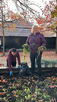 Two volunteers working on a planter. They are holding plants in their hands and working through the soil.