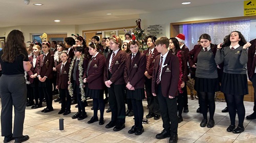 Large school choir performs carols at a festive event in an assisted living community