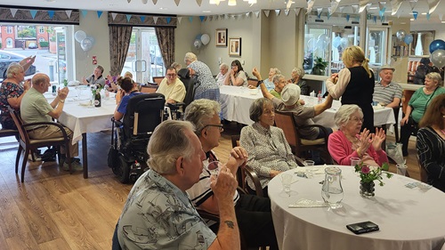 residents and colleagues sat in room around round tables celebrating the anniversary
