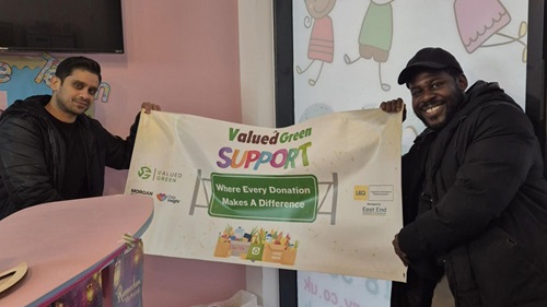 Two men holding a Valued Green SUPPORT banner at Halo Nursery in Hackney, promoting community donations and partnership with L&Q and Morgan Sindall.
