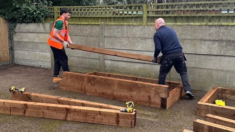 Team building wooden planters in outdoor community space