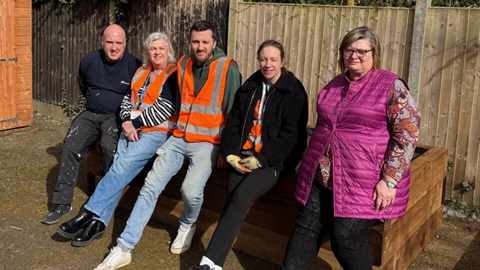 Volunteers sitting on completed wooden planter in community garden project