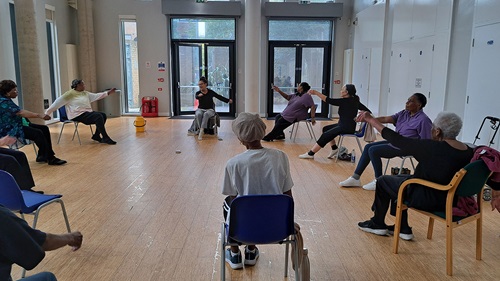 People sat in a circle participating in chair based exercises 