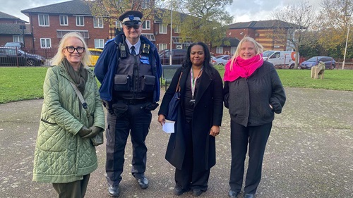 Community safety meeting at Winsor Park estate with housing officer and local police support in outdoor communal area.