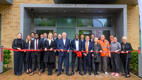 Group of people cutting a red ribbon outside Slessor House, Kidbrooke Village, to mark its official opening.