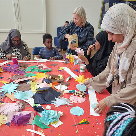 Women and children sat around a table doing arts and crafts