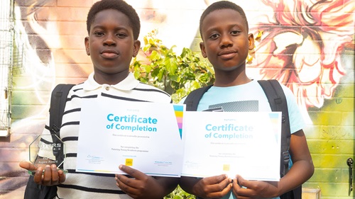 Two pupils display certificates and an award after completing a free Maths and English tutoring programme.