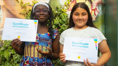 Two pupils hold certificates after completing a free Maths and English tutoring programme.