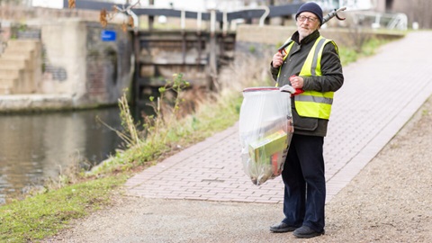 David Bedford stood next to a canal with a litter picker and bag