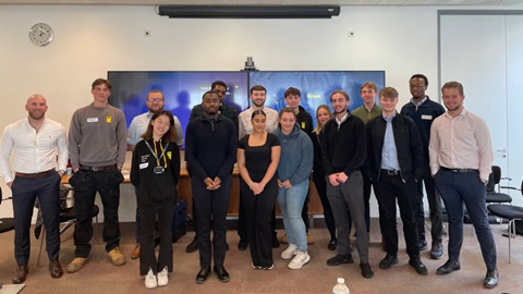 Group of young professionals standing together in an office meeting room.